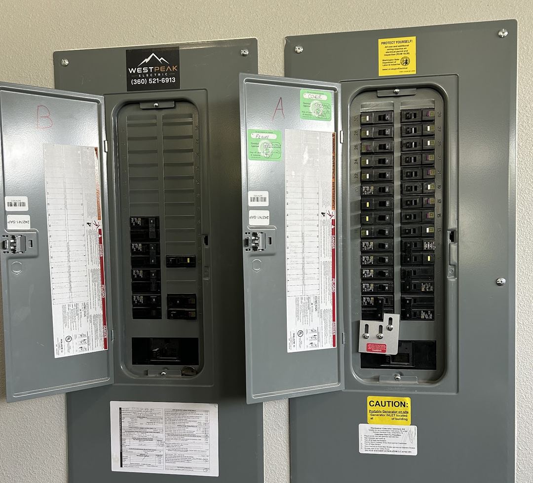 Two gray electrical panels side by side with doors open, labeled A and B, with inspection stickers and a WestPeak Electric label
